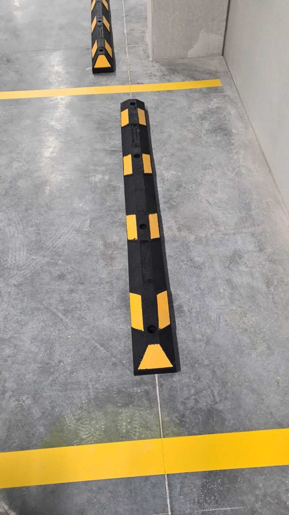 Parkeerplaats met gele markeringen en stoppers